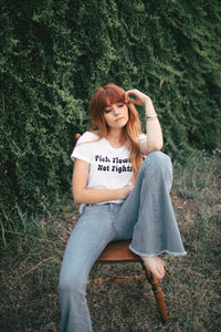 Woman sat on a chair in White Pick Flowers Not Fights Shirt for Women by The Bee and The Fox