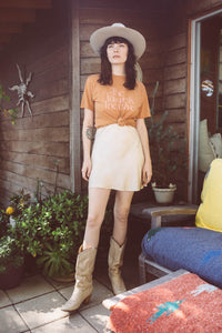 Woman stood outside a house in cowboy boots and wearing The Future is Inclusive Unisex Shirt by The Bee and The Fox